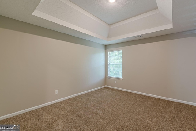 spare room featuring a tray ceiling, carpet, baseboards, and visible vents