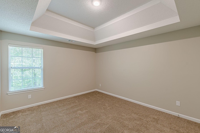 unfurnished room with carpet flooring, a tray ceiling, visible vents, and plenty of natural light