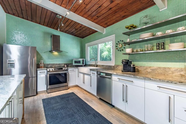 kitchen with stainless steel appliances, wall chimney range hood, a sink, light stone countertops, and wooden ceiling