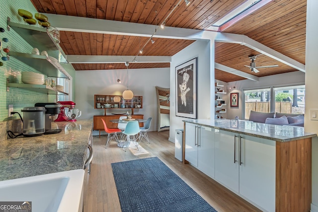 kitchen featuring wooden ceiling, white cabinets, light wood finished floors, a ceiling fan, and stone counters