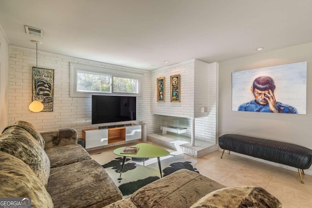 living area featuring tile patterned flooring and brick wall