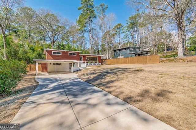 view of front of home with a carport, driveway, and fence