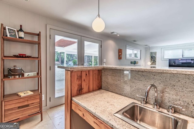 kitchen with a sink, healthy amount of natural light, tasteful backsplash, and light stone counters