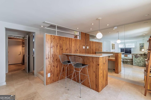 kitchen featuring a breakfast bar area, recessed lighting, decorative light fixtures, a peninsula, and open floor plan