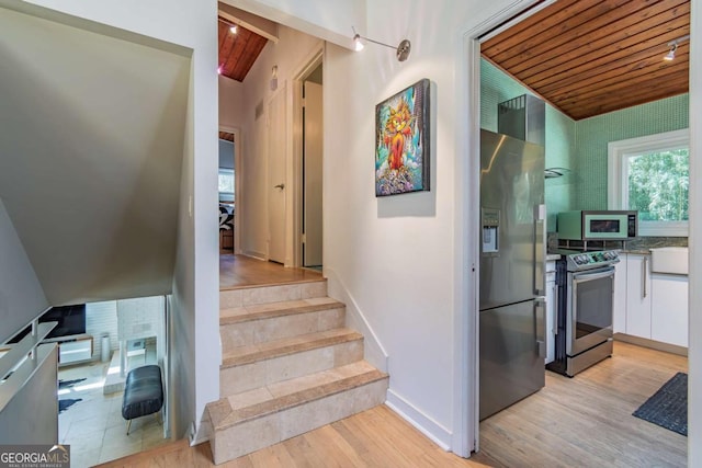 stairway with wooden ceiling, vaulted ceiling, wood finished floors, and baseboards