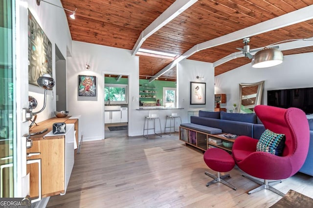 living room with a ceiling fan, beam ceiling, wood ceiling, wood finished floors, and baseboards