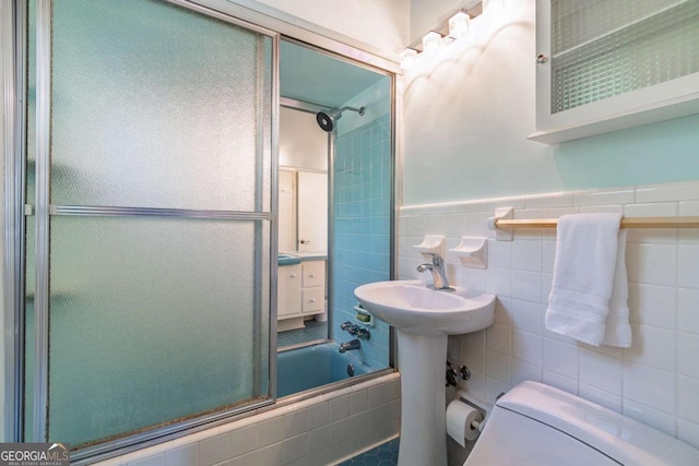 bathroom featuring toilet, tiled shower / bath, and tile walls
