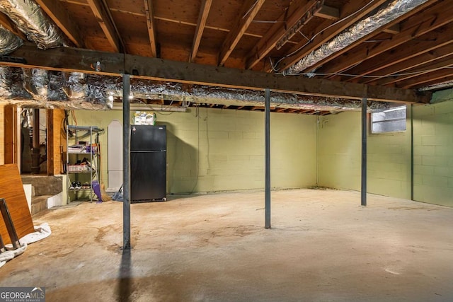 unfinished basement featuring freestanding refrigerator