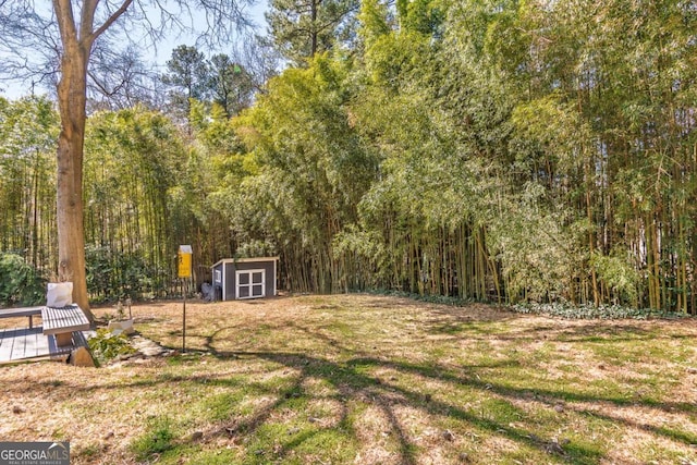 view of yard with a shed, an outdoor structure, and a forest view