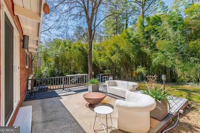 view of patio with a storage shed, an outdoor structure, and view of wooded area