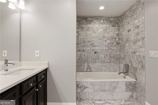 bathroom featuring vanity, tiled shower / bath, and baseboards