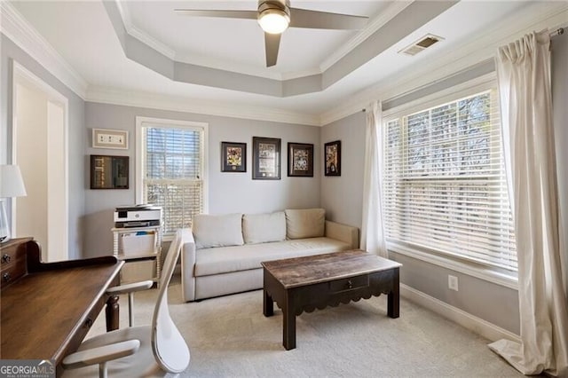 living area featuring visible vents, baseboards, ornamental molding, a raised ceiling, and a ceiling fan