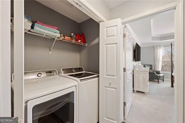 clothes washing area featuring laundry area, ornamental molding, washing machine and dryer, and light carpet