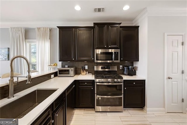 kitchen with a sink, decorative backsplash, light countertops, and stainless steel appliances