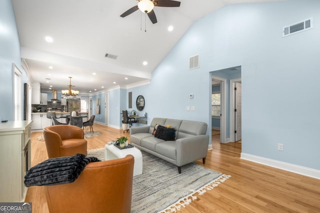 living area with visible vents, baseboards, light wood-style floors, and ceiling fan with notable chandelier