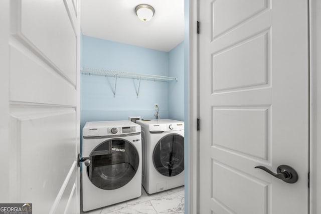 washroom featuring washer and dryer, marble finish floor, and laundry area