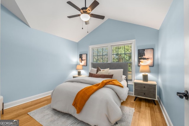 bedroom with baseboards, high vaulted ceiling, wood finished floors, and a ceiling fan