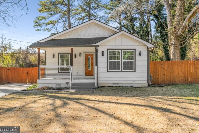 bungalow with fence, covered porch, roof with shingles, a front yard, and crawl space