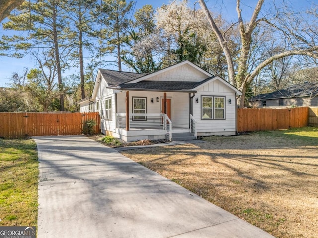 bungalow-style house featuring driveway, a gate, fence, covered porch, and a shingled roof