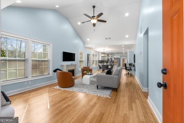 living room with high vaulted ceiling, baseboards, light wood-style floors, and a fireplace