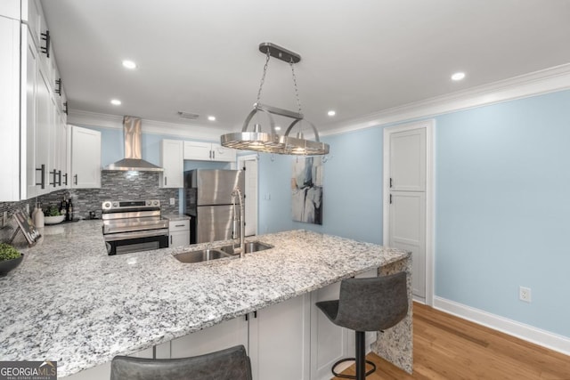 kitchen with light stone counters, backsplash, appliances with stainless steel finishes, wall chimney exhaust hood, and a peninsula