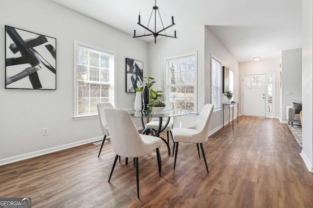 dining room featuring dark wood-type flooring, a notable chandelier, and baseboards