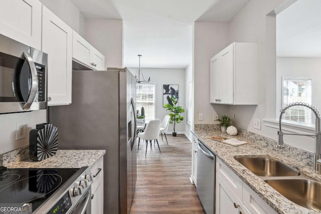 kitchen featuring light stone counters, dark wood-style floors, a sink, appliances with stainless steel finishes, and white cabinetry