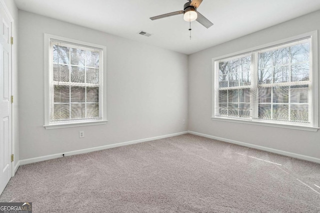 empty room with visible vents, baseboards, carpet, and a ceiling fan