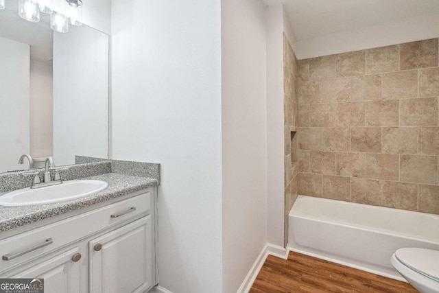 bathroom with vanity, toilet, wood finished floors, and baseboards