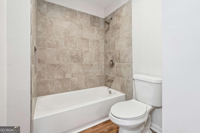 bathroom with toilet, wood finished floors, and shower / bathtub combination