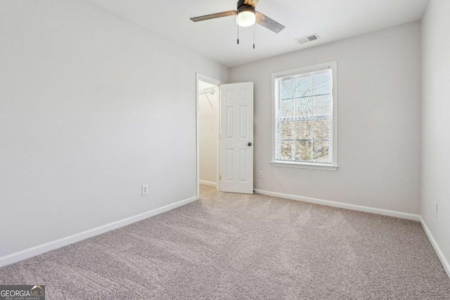 empty room with visible vents, baseboards, a ceiling fan, and carpet flooring