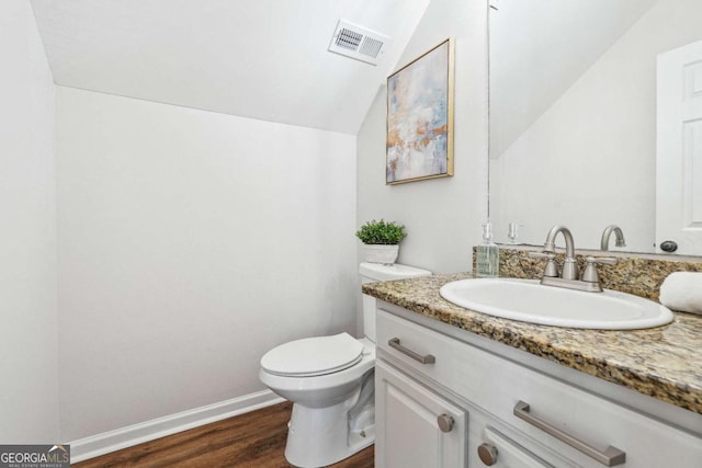 bathroom with visible vents, toilet, wood finished floors, vanity, and vaulted ceiling