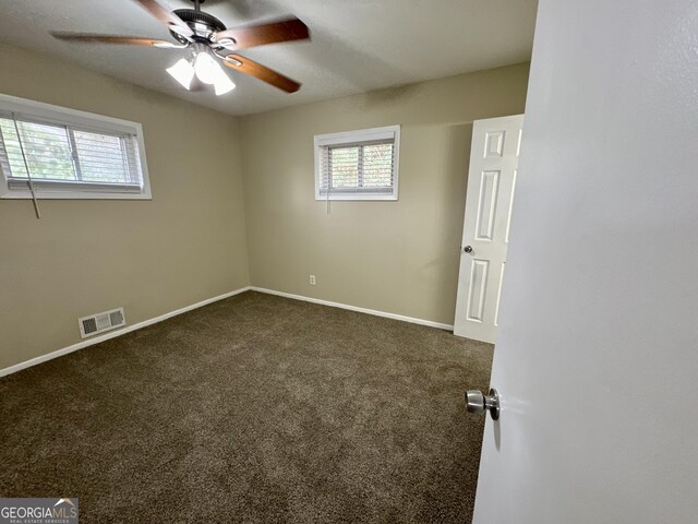 unfurnished room with visible vents, baseboards, a ceiling fan, and dark carpet