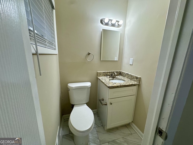 bathroom with marble finish floor, toilet, vanity, and baseboards