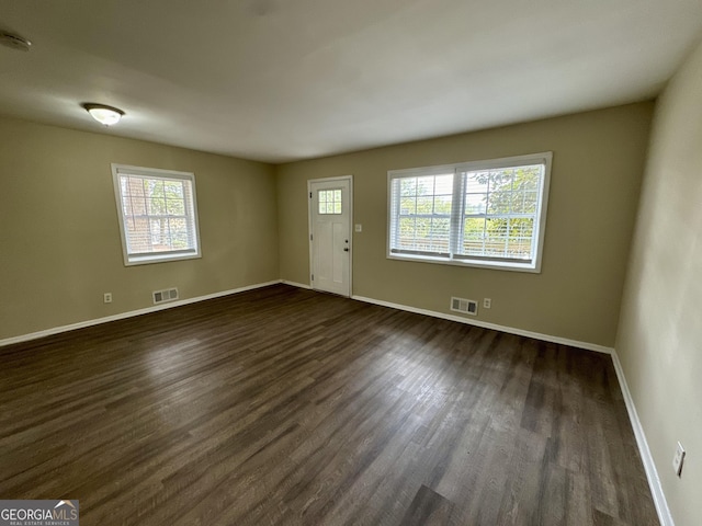 interior space with dark wood-style floors, visible vents, and baseboards