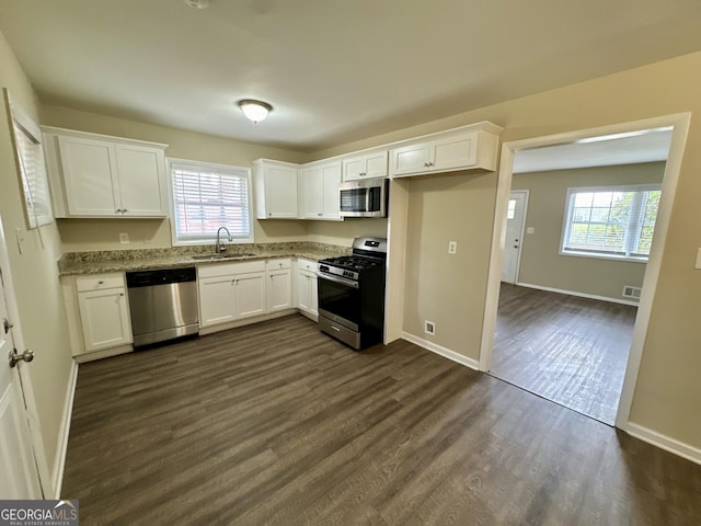 kitchen featuring a healthy amount of sunlight, dark wood-style floors, a sink, stainless steel appliances, and white cabinets