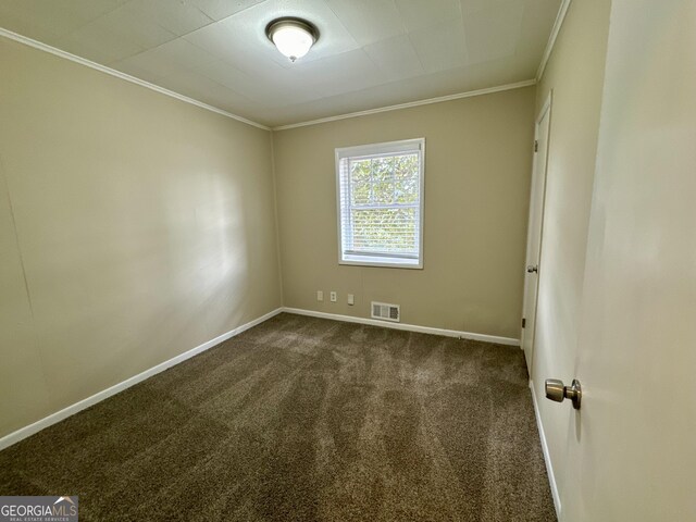 spare room featuring crown molding, baseboards, visible vents, and dark carpet