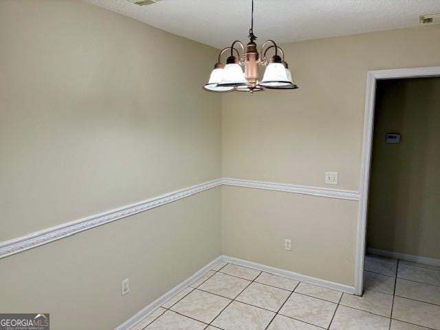 unfurnished dining area with light tile patterned floors, visible vents, baseboards, and a chandelier