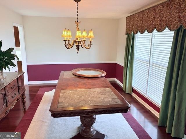 dining area featuring baseboards, a notable chandelier, and dark wood-style flooring