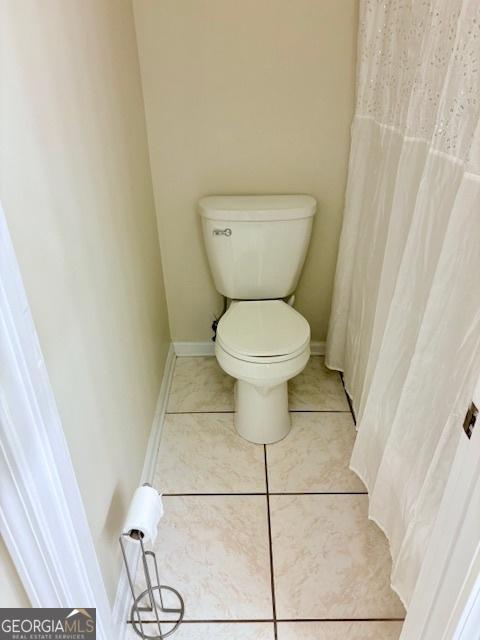 bathroom with tile patterned flooring, toilet, and baseboards