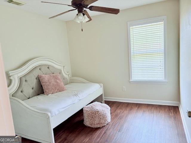 bedroom featuring visible vents, ceiling fan, baseboards, and wood finished floors