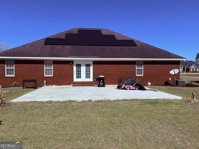 rear view of house with a yard, a patio, and brick siding