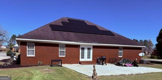 back of property featuring a patio, a yard, entry steps, french doors, and brick siding