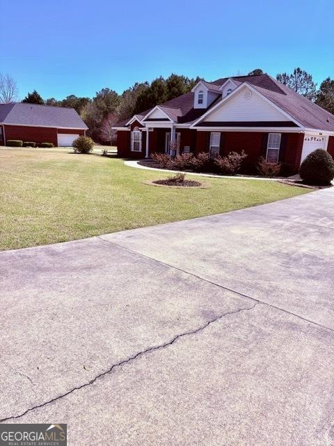 view of front of house featuring a garage, concrete driveway, and a front lawn