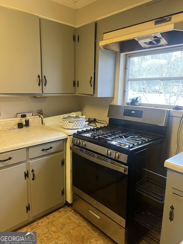 kitchen with under cabinet range hood, stainless steel gas range, and light countertops