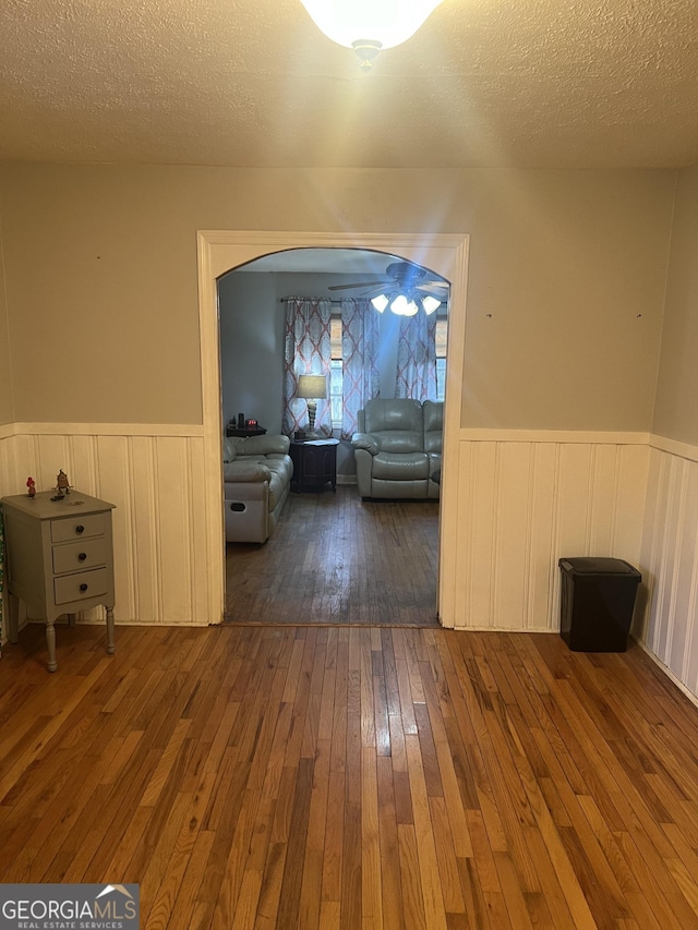 interior space featuring a textured ceiling, hardwood / wood-style flooring, and wainscoting