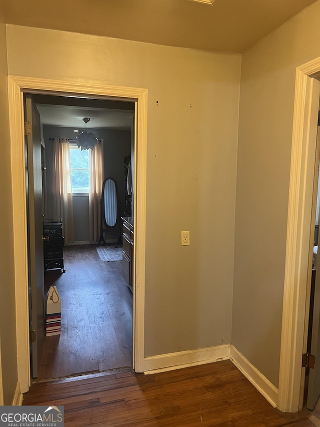 corridor with baseboards and wood-type flooring