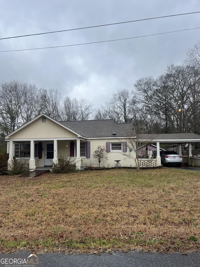 view of front of house featuring a carport, covered porch, and a front yard