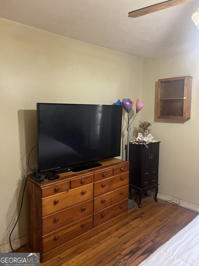 bedroom with baseboards, a textured ceiling, and wood finished floors