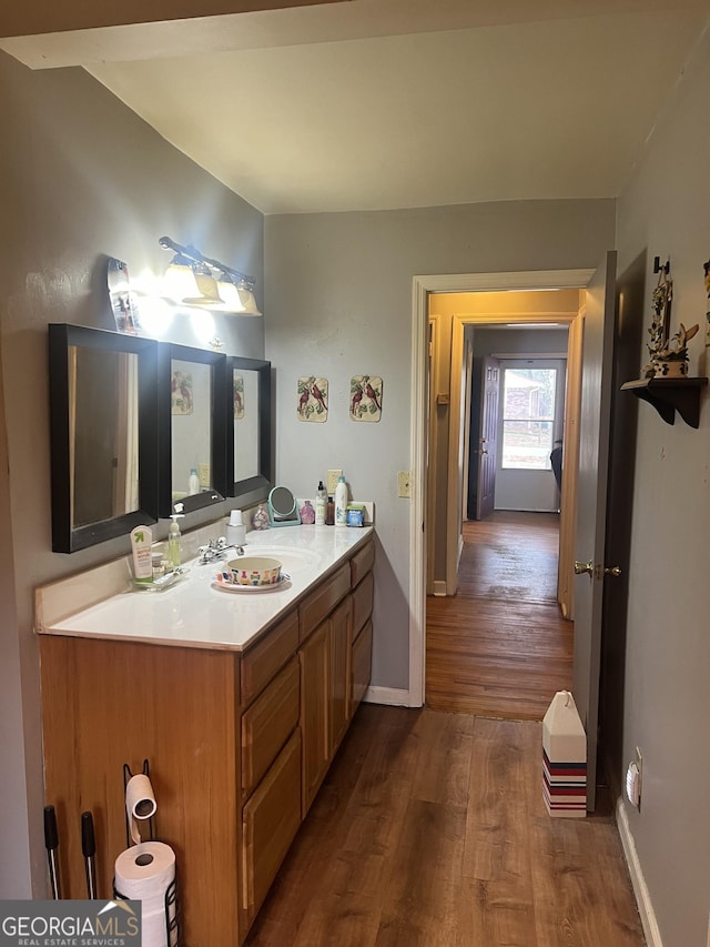 bathroom featuring vanity, wood finished floors, and baseboards